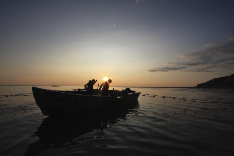 Two people fishing on a boat at sunset near Naknek,AK