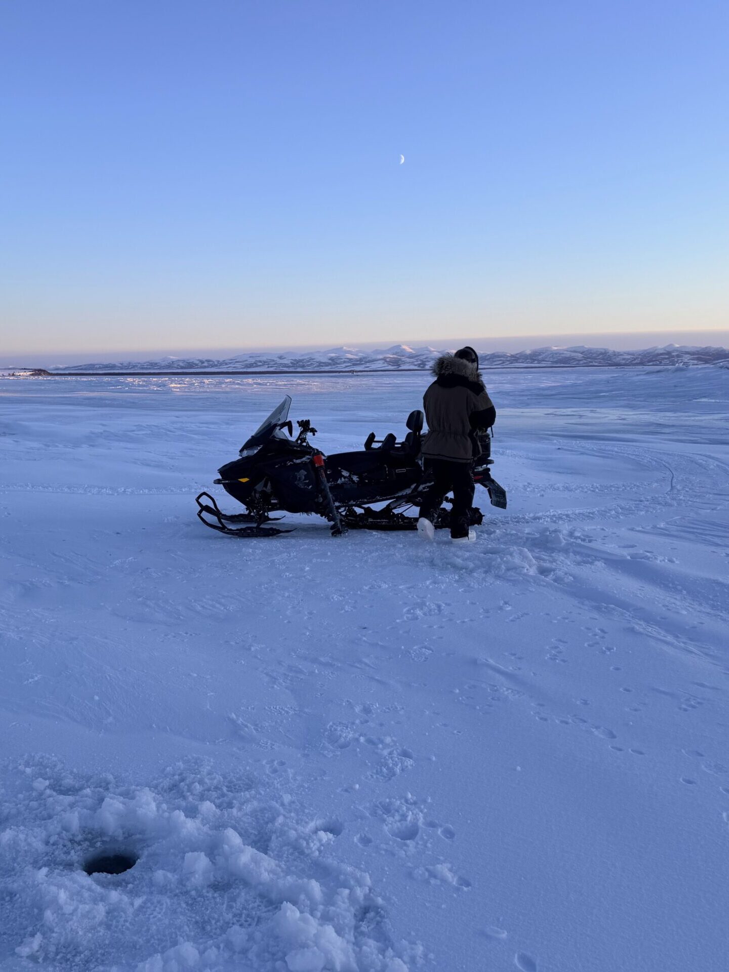 Person walking to snowmobile in Naknek