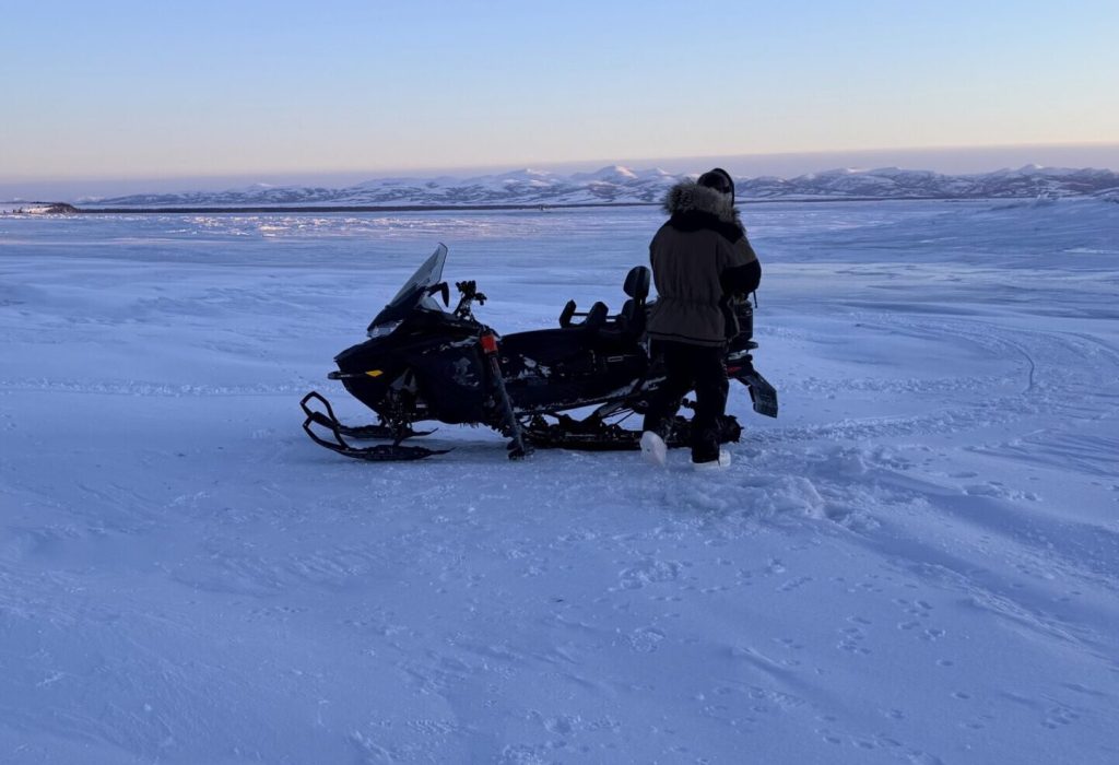 Person walking to snowmobile in Naknek